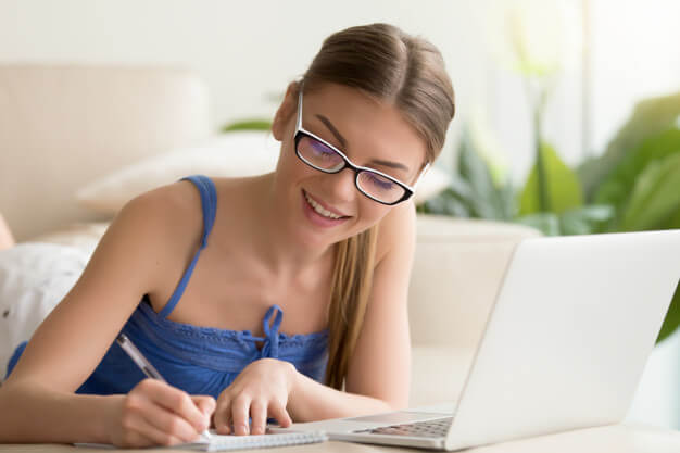 menina de óculos sorrindo e estudando online