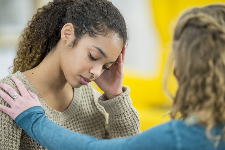 Menina com expressão triste conversando com outra garota