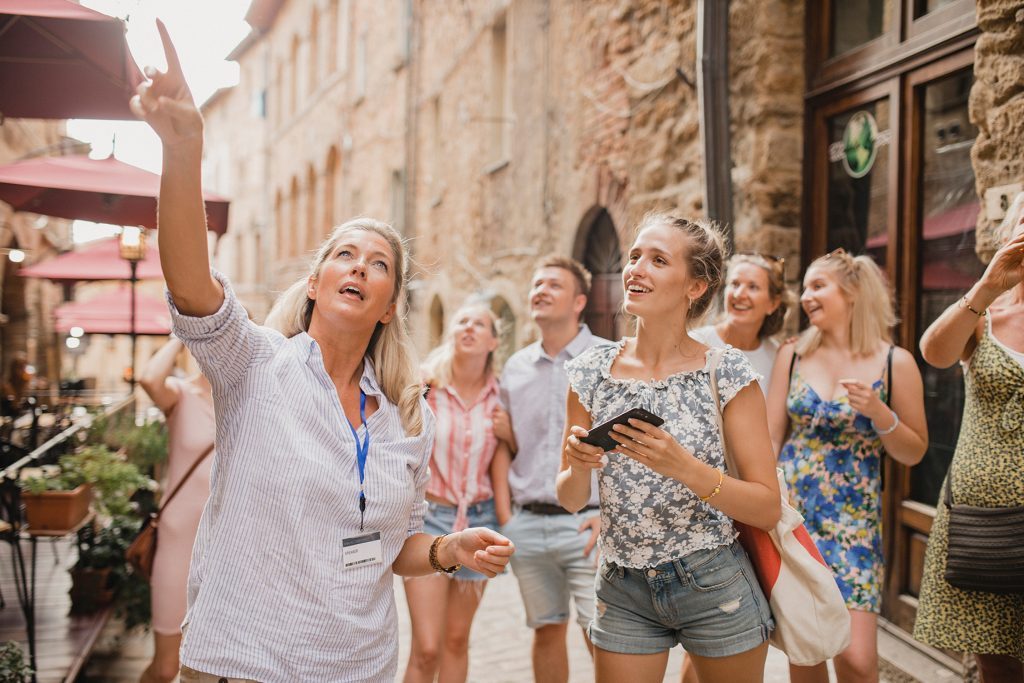 Trabalhar viajando: o seu sonho pode se tornar realidade A imagem mostra uma guia turística apresentando para os turistas um ponto histórico